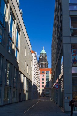 Dresden, Almanya - 31 Ağustos 2025: Dresden 'de bir sokak boyunca Frauenkirche Dresden Kubbesi' ne doğru modern binaların üzerine bakın. Sıcak ışık ve gölgeler koridoru kapatıyor. Mavi gökyüzü taşın zıttı..