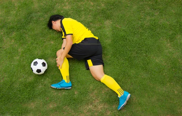 Football player in Yellow lying injured on the pitch. — Stock Photo, Image