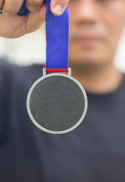 Atleta segurando medalha de ouro genérica com fita em sua mão . — Fotografia de Stock