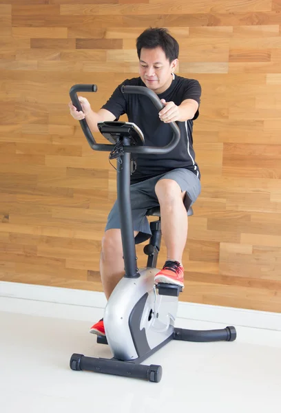 Asiatiska mannen på motion cykel på gym. — Stockfoto