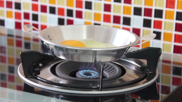 Αυγό ραγίσει και ρίξτε τα στο τηγάνι μια σιδήρου, όπου ξεκινά τηγάνισμα σε μια σόμπα αερίου. — Αρχείο Βίντεο