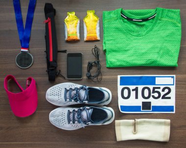 Ana sayfa görünümü koşu ayakkabıları, maraton yarışı Bib (sayı), madalya, koşucular dişli ve enerji jelleri ahşap arka plan, spor, Fitness ve sağlıklı yaşam konsepti.