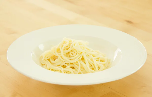 Spaghetti in piatto bianco per cucinare su sfondo di legno — Foto Stock