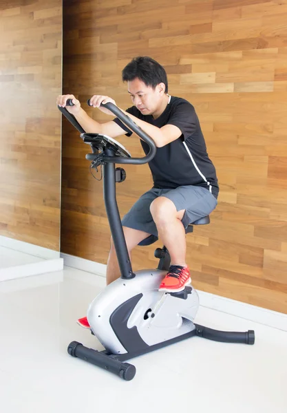 Asiático hombre en ejercicio bicicleta en gimnasio . —  Fotos de Stock