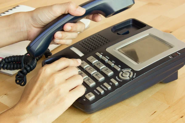 Receptor de teléfono de mano femenina y número de marcación en el lugar de trabajo — Foto de Stock