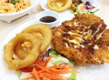 Kızarmış balık bifteği ve masada soğan kızartması..