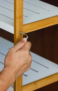 Asyalı adamın el vida yukarıya hex anahtar ile ahşap raf.