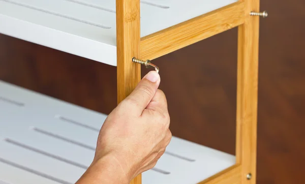 Asian man's hand screw up wooden shelf with hex wrench. — Stock Photo, Image