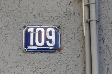 109 numara, ev, daire, sokak sayısı. Mavi metal bir plakadaki beyaz numara, kabataslak bir duvardaki 109 numaralı ev..