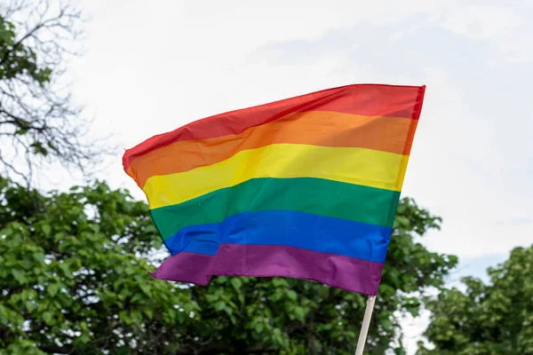 The flag on gay pride parade, Rainbow flag, a symbol for the LGBT community, waving in the wind with a cloudy background
