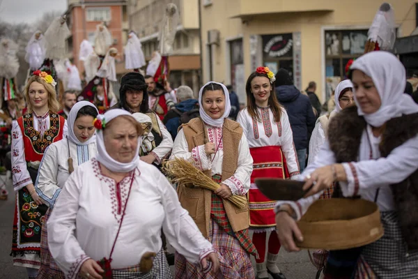 Kyustendil, Bulgaristan 07 Şubat 2026: Djamala Maskeli Balosu. Koyun postu giymiş ve yüzü boyalı bir kadın. Arkasında, ahşap boynuzlu bir maske vardı. Kötü ruhları defetmek için yapılan geleneksel ayinin bir parçasıydı..