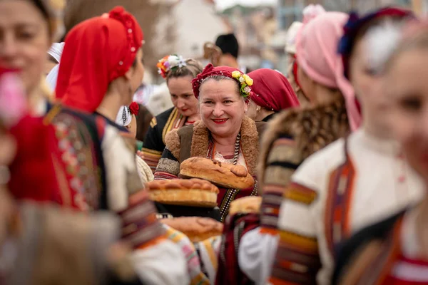 Kyustendil, Bulgaristan 07 Şubat 2026: Djamala Maskeli Balosu. Koyun postu giymiş ve yüzü boyalı bir kadın. Arkasında, ahşap boynuzlu bir maske vardı. Kötü ruhları defetmek için yapılan geleneksel ayinin bir parçasıydı..