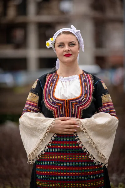 Kyustendil, Bulgaristan 07 Şubat 2026: Djamala Maskeli Balosu. Koyun postu giymiş ve yüzü boyalı bir kadın. Arkasında, ahşap boynuzlu bir maske vardı. Kötü ruhları defetmek için yapılan geleneksel ayinin bir parçasıydı..