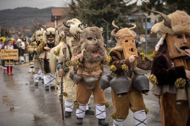 Novi Iskar, Bulgaristan, 15 Şubat 2026: Geleneksel deri kostümlü, büyük ayin çanları ve oyulmuş ahşap maskeli Kukeri, kötü ruhların sürgün edilişini ve refah ortamını simgeliyor..