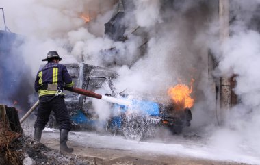 İtfaiyeci yanan bir arabadan söndürmek