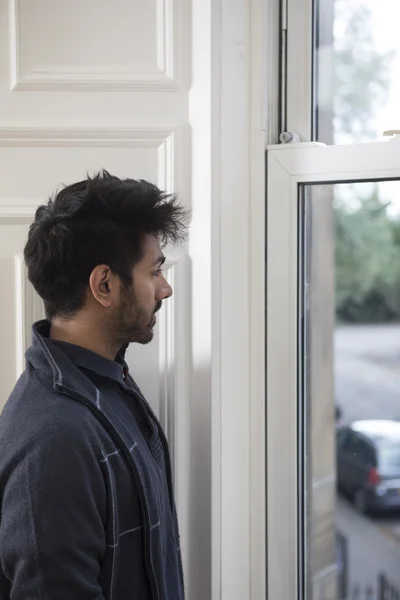 Asian man looking out of window