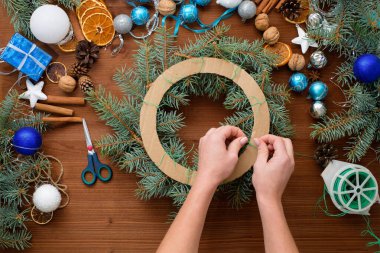 2021 boğasının gümüş ve mavi renklerinde ladin dalları, portakallar ve Noel toplarından evde adım adım bir Noel ağacı çelengi yapma süreci. tahta arkaplan üst görünümü.