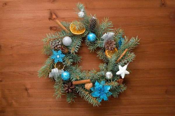 home made Christmas tree wreath made of fir branches on a wooden background with blue and silver balls in the colors of 2021 bull.