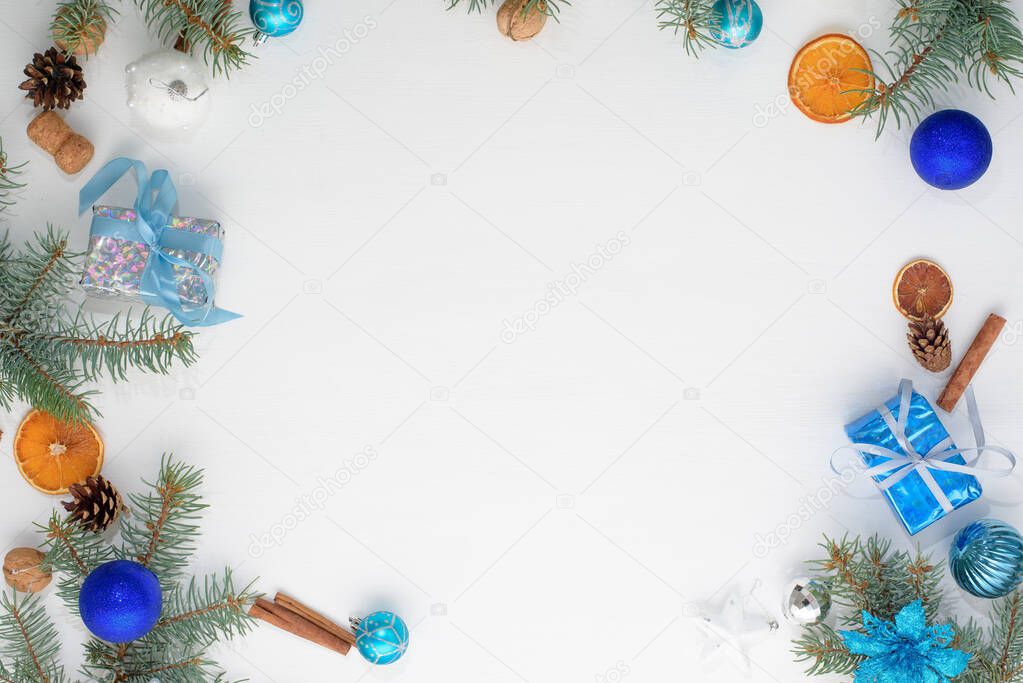Christmas light background with a frame of fir branches and balls of blue and silver flowers, gifts and cones. the 2021 bull color trend.