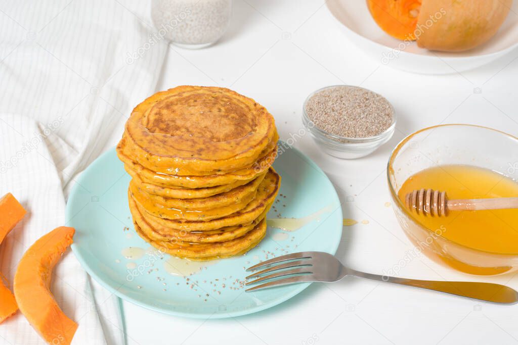 a stack of autumn pumpkin pancakes with Chia seeds and honey on a light background. delicious healthy vegetarian diet Breakfast. the concept of taking care of your body, the keto diet