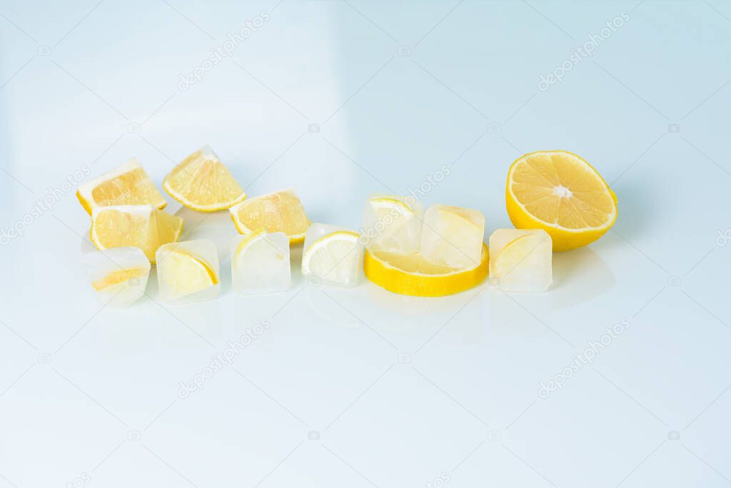 cosmetic ice cubes with lemon and vitamin C for skin care on a blue light background, natural organic ingredients for home care, detox. place for text.