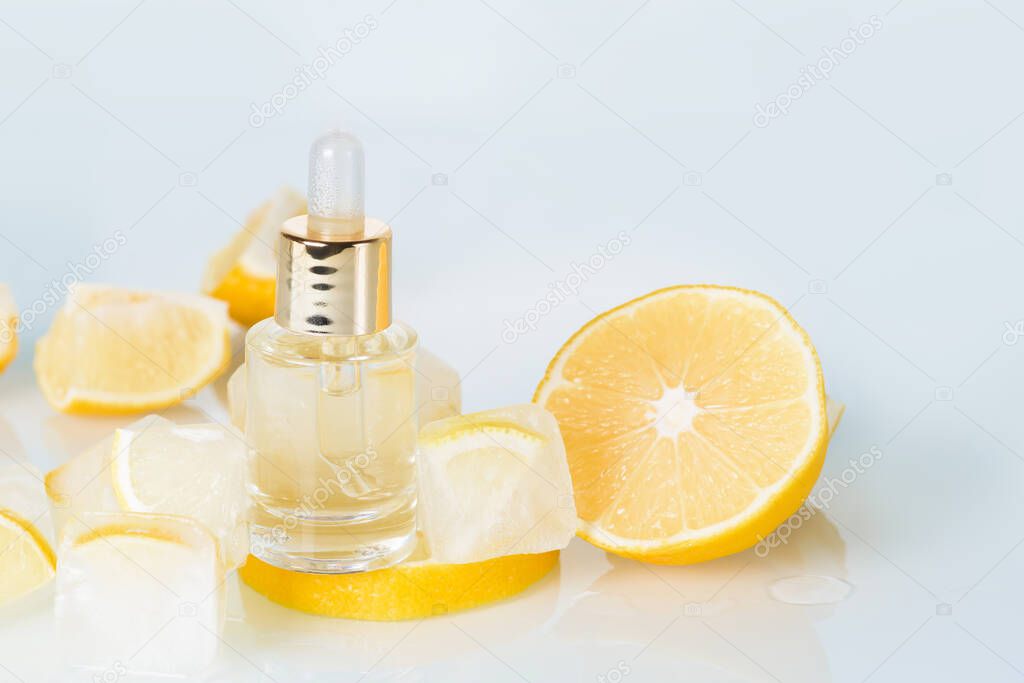 face serum with lemon, cosmetic ice cream with lemon and vitamin C for skin care on a blue light background, natural organic ingredients for home care, detox. place for text.