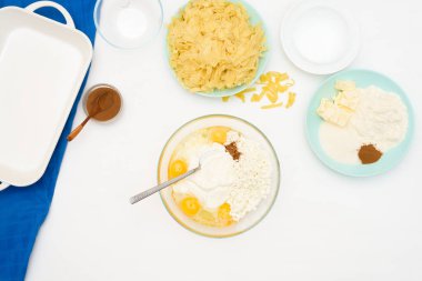Hanuka bayramı için adım adım tarif, erişte ve kremalı geleneksel bir Kugel turtası, tepesinde kum kırıntıları. Tabaklardaki malzemeler arka planda, üst tarafta. karıştırma ürünleri.