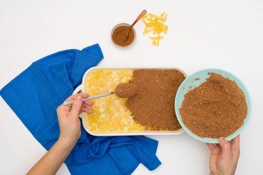 Hanuka bayramı için adım adım tarif, erişte ve kremalı geleneksel bir Kugel turtası, tepesinde kum kırıntıları. Tabaklardaki malzemeler hafif arka planda. Yemekleri pişirme kabında karıştırmak..