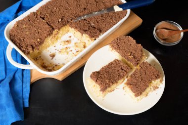 Hanuka bayramı, erişteli ve kremalı geleneksel tatlı Kugel turtası üstüne de küçük kakao kırıntıları. Pişirme kabında hafif bir arka planda. Bir tabakta pasta dilimleri.