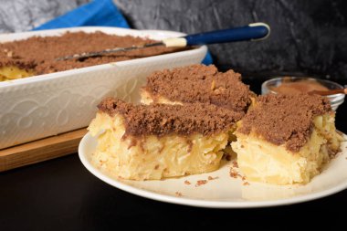 Hanuka bayramı, erişteli ve kremalı geleneksel tatlı Kugel turtası üstüne de küçük kakao kırıntıları. Pişirme kabında hafif bir arka planda. Bir tabakta pasta dilimleri.