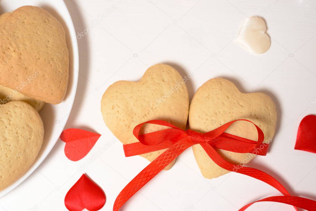 cookie heart tied with red ribbon for Valentine's day, close-up, baking for the holiday. decorative hearts top view.