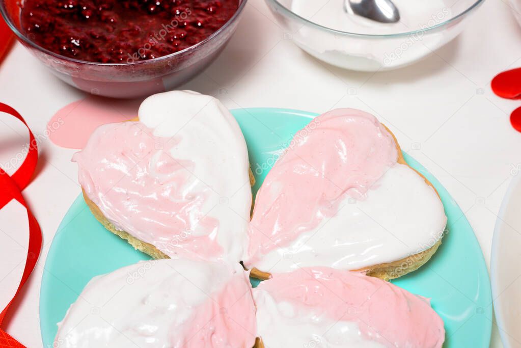 cookie heart decorated with glaze white and pink for Valentine's day, close-up, baking for the holiday. decorative hearts top view.