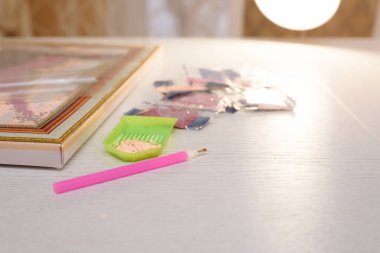 ev hobisi yapay elmasların resmini çizmek, çok renkli elmas mozaiği. Resmin tuvaline yapay elmaslardan bir kalem yapıştırma işlemi.