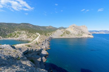 Deniz dağı kıyısının panoraması, Kırım Karadeniz kıyısı güneşli bir günde. Kıyıdaki kayalar, mavi gökyüzü.