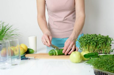 Adım adım mikro-yeşil elma salatalığı ve ıspanaktan meyve püresi yapma tarifi. Kadın elleri sebzeleri kesiyor ve onları miksere koyuyor. Hafif arka planda organik gıda detoksu için çırpıyorlar..