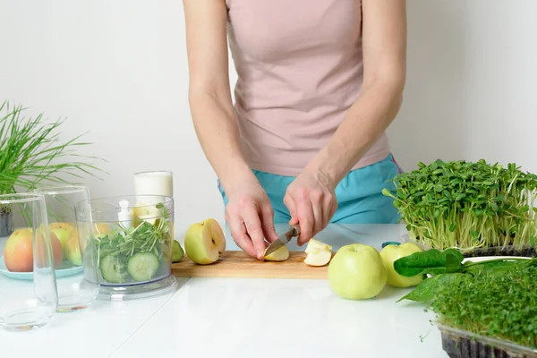 Adım adım mikro-yeşil elma salatalığı ve ıspanaktan meyve püresi yapma tarifi. Kadın elleri sebzeleri kesiyor ve onları miksere koyuyor. Hafif arka planda organik gıda detoksu için çırpıyorlar..