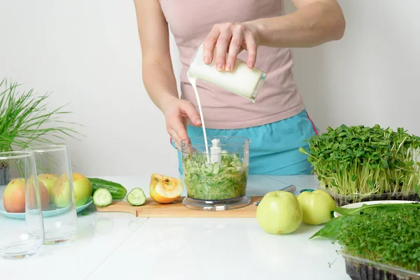 step-by-step recipe for making smoothies from micro-green apples cucumber and spinach. woman hands cut vegetables and put them in blender for whipping eco organic fresh food detox on light background.