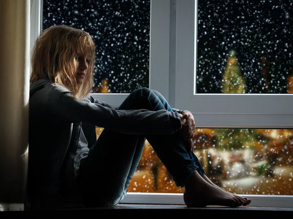 Girl sits on the window. Outside, winter city