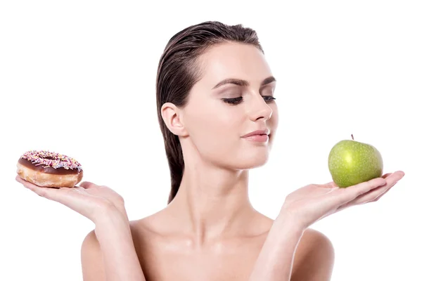 Woman holding doughnut and apple — Stock Photo, Image