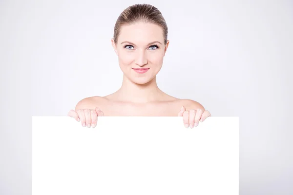 Mulher se escondendo atrás de quadro branco em branco — Fotografia de Stock