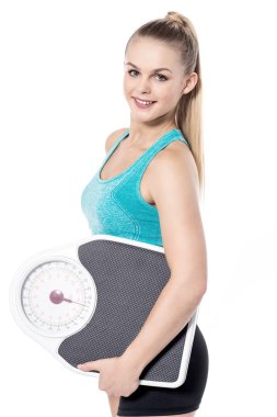 bir ağırlık ölçek tutan genç kadın