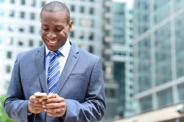 onun smartphone kullanarak gülümseyen iş adamı