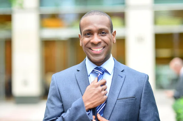 Smiling businessman adjusting his tie — Stock Photo, Image