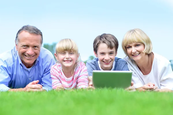 Family lying on grass in park — Stock Photo, Image
