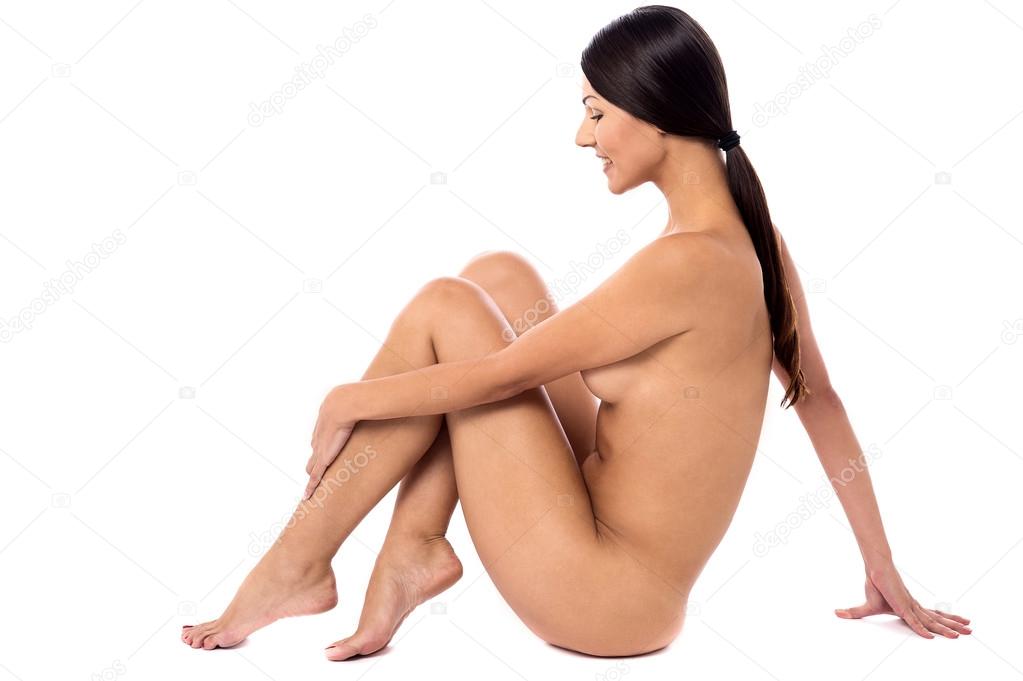 Download - Side view young naked woman sitting on floor - Stock Image. 