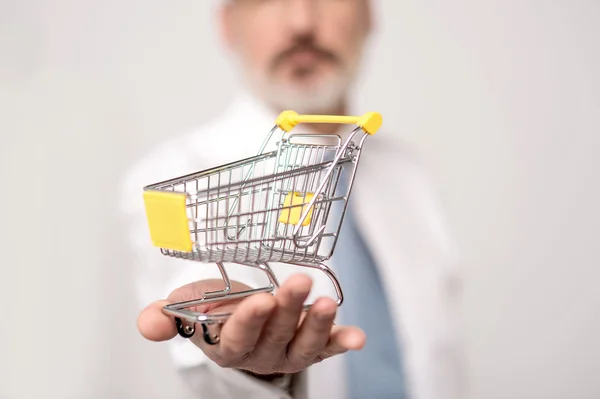 Businessman showing mini shopping cart — Stock Photo, Image