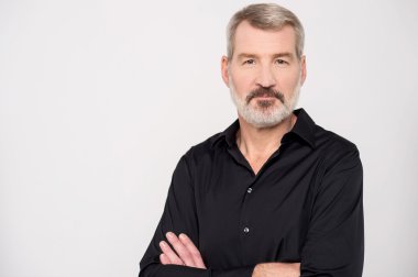 Kollarını kavuşturmuş olgun bir adam.