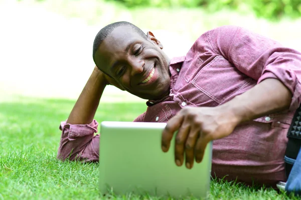 Mann liegt mit Tablet auf Rasen — Stockfoto