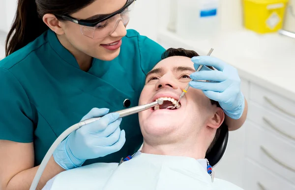 Асистент стоматолога лікує пацієнта чоловічої статі — стокове фото