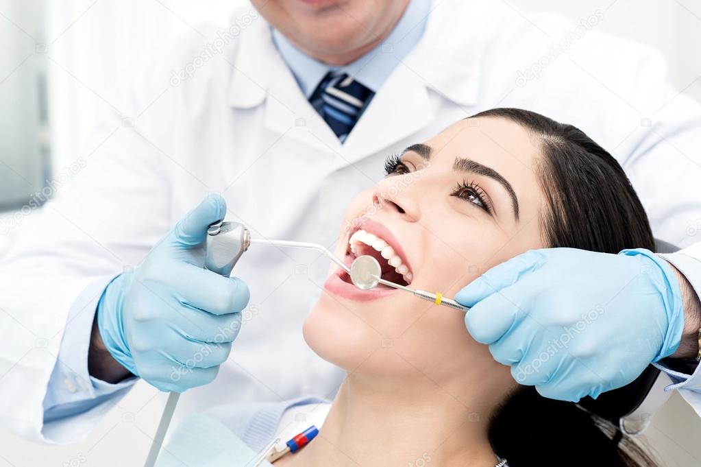 Male dentist whitening the woman teeth